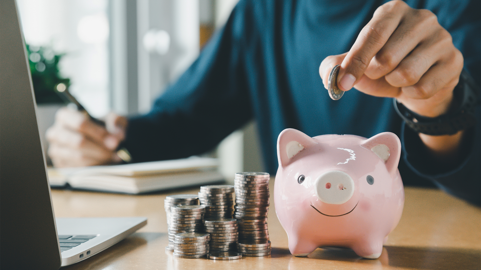 Hand putting coins in a piggy bank